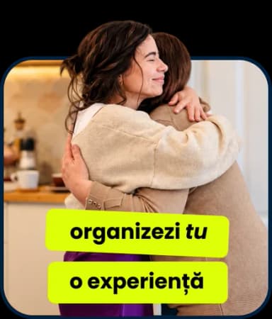 Două femei se îmbrățișează într-o bucătărie: „organizezi tu o experiență”